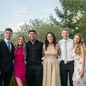 Group of students smiling in formal clothes outside.