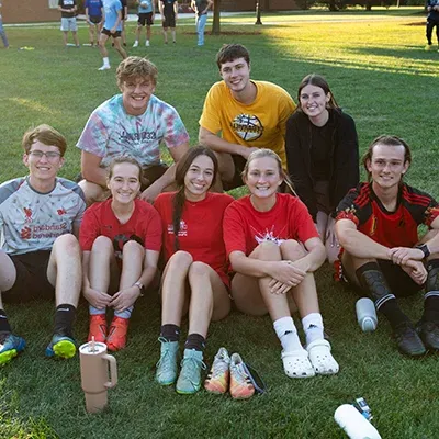 Students smiling outside and resting from soccer game.