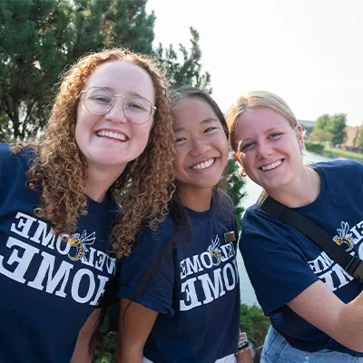 Three college students in Welcome Home shirts.